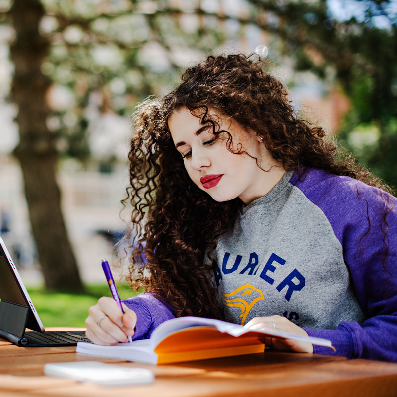 A white female student studying outside.